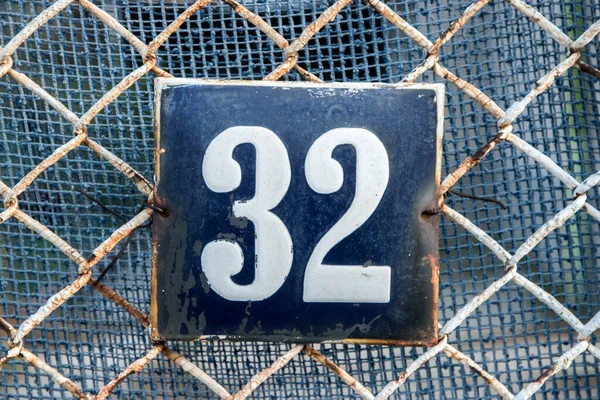 Weathered grunge square metal enameled plate of number of street address with number 32
