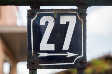 Yıpranmış, köhne, metal plakalı, 27 numaralı sokak adresi.
