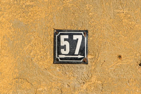 Weathered grunge square metal enameled plate of number of street address with number 57