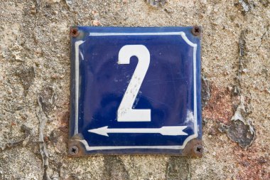 İki numaralı sokak adresinin plakası işlemeli eski püskü, kare bir metal.