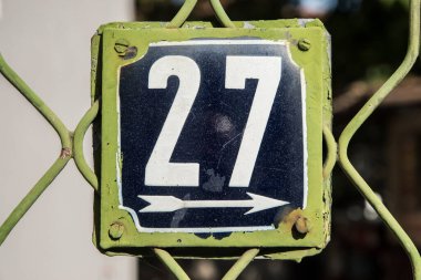 Yıpranmış, köhne, metal plakalı, 27 numaralı sokak adresi.