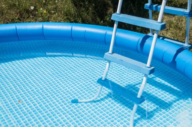 Mavi yuvarlak lastik şişirilebilir aile havuzu detayı ve merdiveni yakın plan.