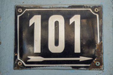 Yıpranmış kare metal plaka numarası 101 olan sokak adresi.