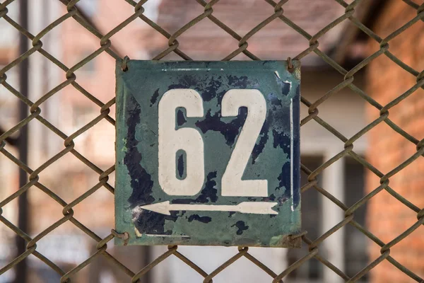 Weathered grunge square metal enameled plate of number of street address with number 62