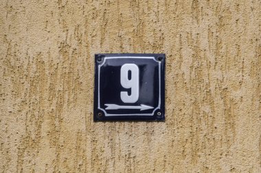 Yıpranmış, köhne, metal plakalı, üzerinde 9 numara olan sokak adresi.