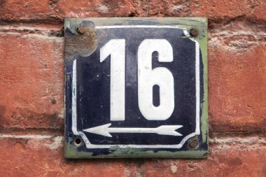 Yıpranmış kare metal plakalı sokak adresi numarası 16.