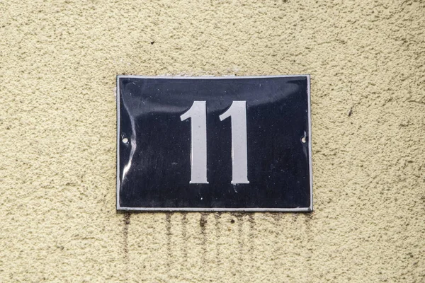 Weathered grunge square metal enameled plate of number of street address with number 11