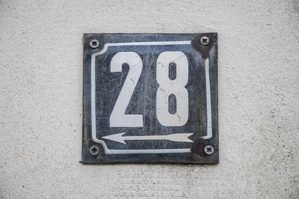 Weathered grunge square metal enameled plate of number of street address with number 28 isolated on white background