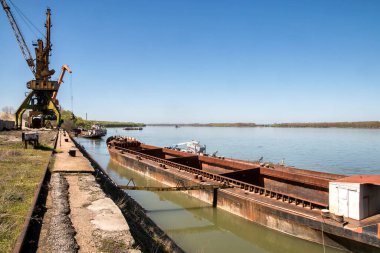 Nehir boyu kargo mavnası ve sanayi vinçleri güneşli bir günde nehir limanında