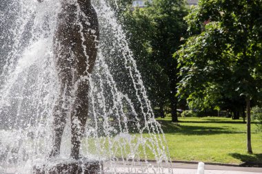 Güneşli bir yaz gününde, şehir parkındaki çeşme su sıçratır.