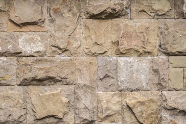 Solid house stone wall of roughly hewn stone closeup as stone background