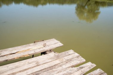 Kırsal kesimde güneşli bir günde göl kıyısındaki ahşap iskele.
