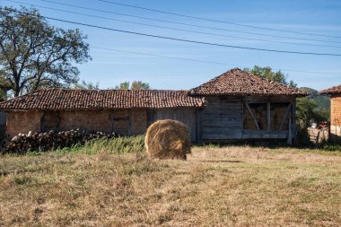 Sonbaharda kırsal kesimde saman balyası olan eski bir çiftlik evi.