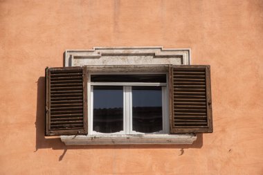 Roma, İtalya 'da turuncu bir duvarda kepenkleri olan eski ahşap bir pencere.