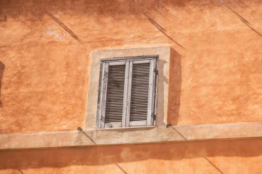 Roma, İtalya 'da turuncu duvarda panjurları olan eski bir pencere.