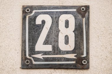 28 numarayla birlikte yıpranmış bir plaka.