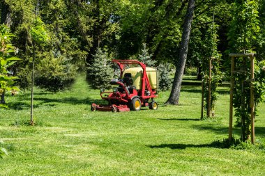 Baharda şehir parkında çim biçme makinesinde profesyonel çok işlevli gezinti.