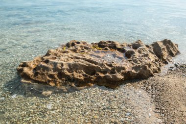 Güneşli yaz gününde kumsalda sakin deniz sularında aşınmış güzel bir taş.