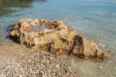 Güneşli yaz gününde kumsalda sakin deniz sularında aşınmış güzel bir taş.