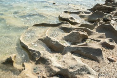 Güneşli yaz gününde kumsalda sakin deniz sularında aşınmış güzel bir taş.