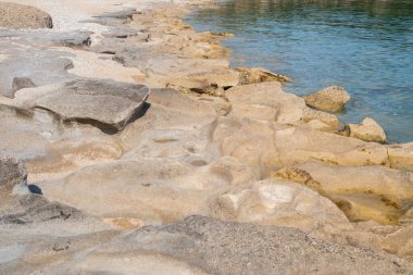 Güneşli yaz gününde kumsalda sakin deniz sularında aşınmış güzel bir taş.