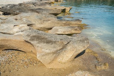Güneşli yaz gününde kumsalda sakin deniz sularında aşınmış güzel bir taş.
