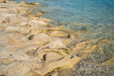 Güneşli yaz gününde kumsalda sakin deniz sularında aşınmış güzel bir taş.
