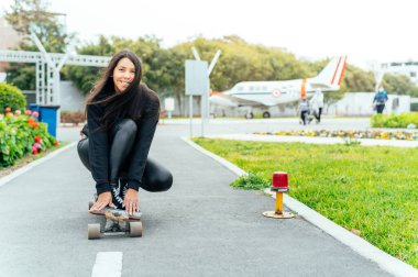 Young girl on longboard smiling. Outdoors, lifestyle