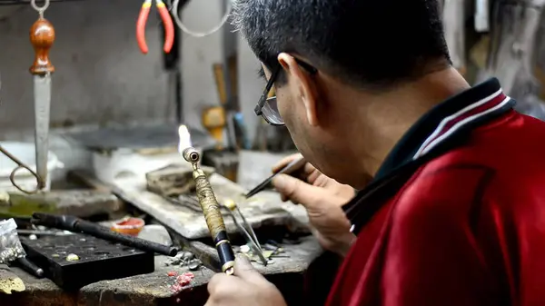 Master jeweler welding an ornament in a jewelry workshop. Image of hands and product close up.