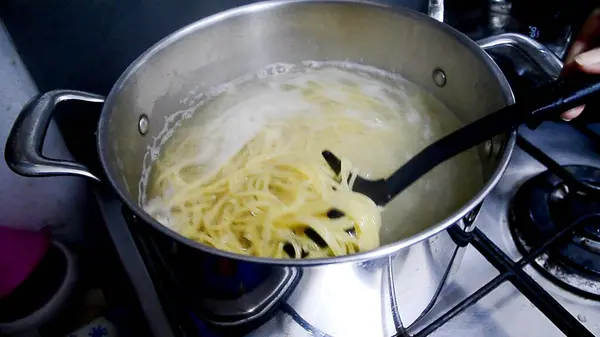 Boiled water with noodle in a kitchen pot on the stove. Bubbling of hot water