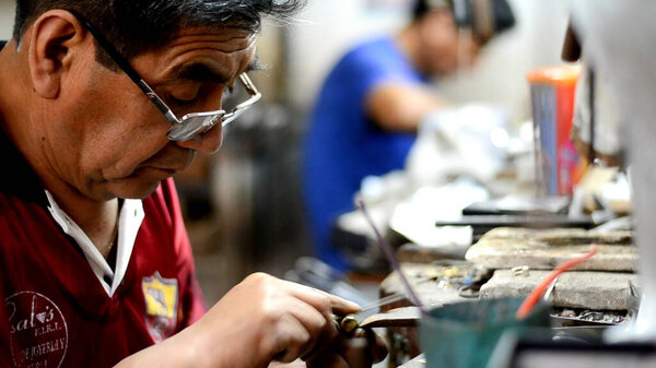 Master jeweler polishing an ornament in a jewelry workshop. Image of hands and product closely.