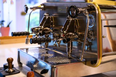 Parlak bir espresso makinesinin yakın plan çekimi kahve demlenmeye hazır.