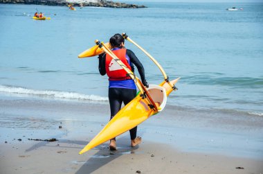 Sahilde kayak yapmaya hazırlanan birinin sarı bir kano taşıdığını gördüm.