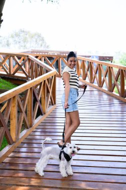 Şehir merkezinde sakin bir yolda köpeğini gezdiren genç bir kadın.