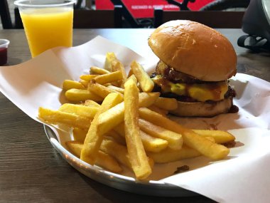 Tahta masada taze portakal suyu ve kızarmış patatesli nefis bir çizburger.