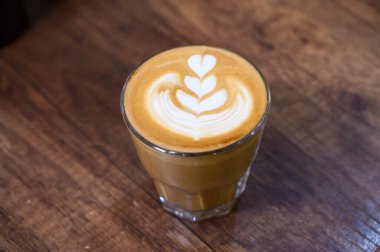Tahta masada kalp şeklinde latte ile taze demlenmiş latte.