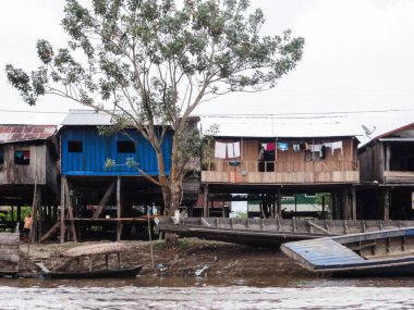 Nehir kıyısında birkaç ahşap ev var. Belen bölgesinin ortasında mavi bir ev, iquitos, Peru.