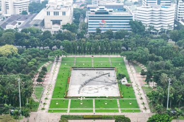 Merdeka Meydanı 'nın havadan görünüşü, jakarta merkezinde geniş bir açık alan, yeşil çimenleri, ağaçları, göleti ve çevresindeki binaları gösteriyor.