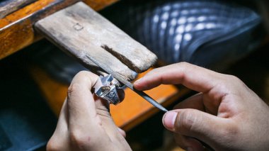 Goldsmith bir dosya ile gümüş bir yüzük şekillendiriyor.