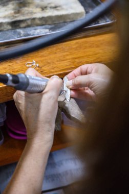 Goldsmith atölyeye gümüş bir kolye oyuyor.