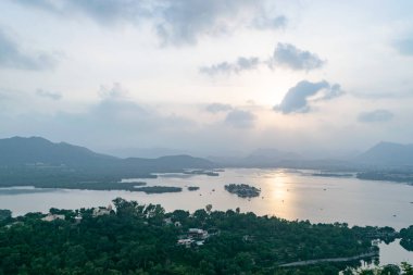 Güneşin son ışınları Udaipur, Hindistan 'daki tepeler ve saraylarla çevrili Pichola Gölü' ne yansıyor.