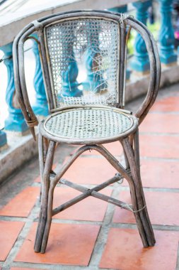 Yıpranmış iskemle fayanslı zeminde duruyor, kırık koltuğunu ve yıpranmış görünüşünü gösteriyor, Kamboçya 'da terk edilme ve çürüme hissi uyandırıyor.