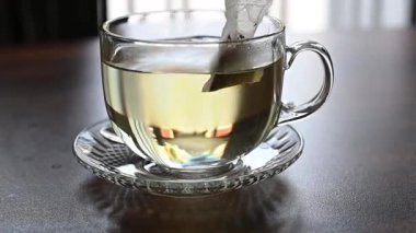 Tahta bir masada şeffaf bir fincan sıcak çay.