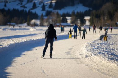 Weissensee, Avusturya - 8 Şubat 2022: Weissensee Gölü (Avusturya) Kışın güneşli bir günde insanlar buz pateni yapıyor
