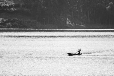 Kabale, Uganda - 12 Haziran 2022: Bunyonyi Gölü 'nde (Uganda) bir kanodaki adam, yazın güneşli bir gün