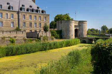 Bergues, France - July 5. 2022: An old city wall with surveillance towers, city gate and bridge, clear day, blue sky