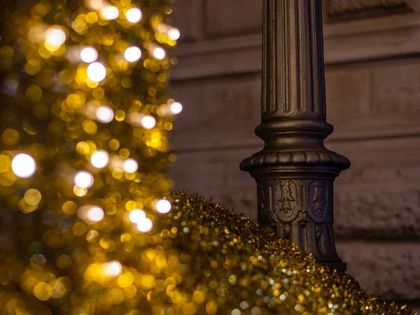 shiny golden street decoration in front of a street lamp at nighttime at christmas in Vienna, Austria