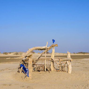 Camargue 'deki Salin-de-Giraud (Provence, Fransa) yakınlarında kumlu bir sahilde ağaçtan yapılmış bir barınak ilkbaharda güneşli bir günde, mavi gökyüzü