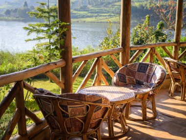 Ugandan Gölü 'nün yanındaki ahşap terasta sandalyeli ahşap bir sehpa.