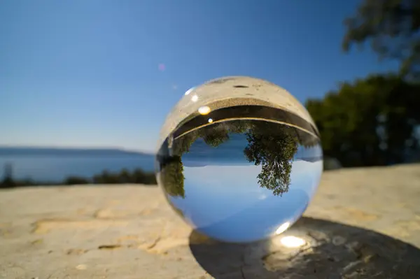 A glass sphere lying on a stone wall in Cres (Croatia), sunny day in springtime, blue sky